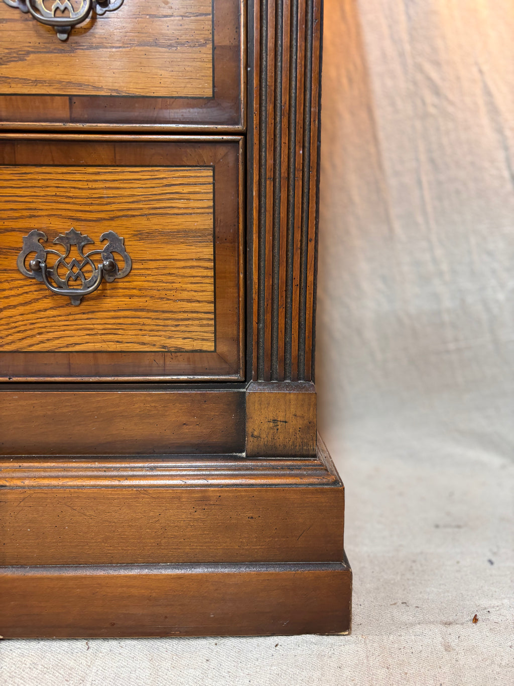 Close-up of a wooden drawer with a metal handle on a light-colored floor.