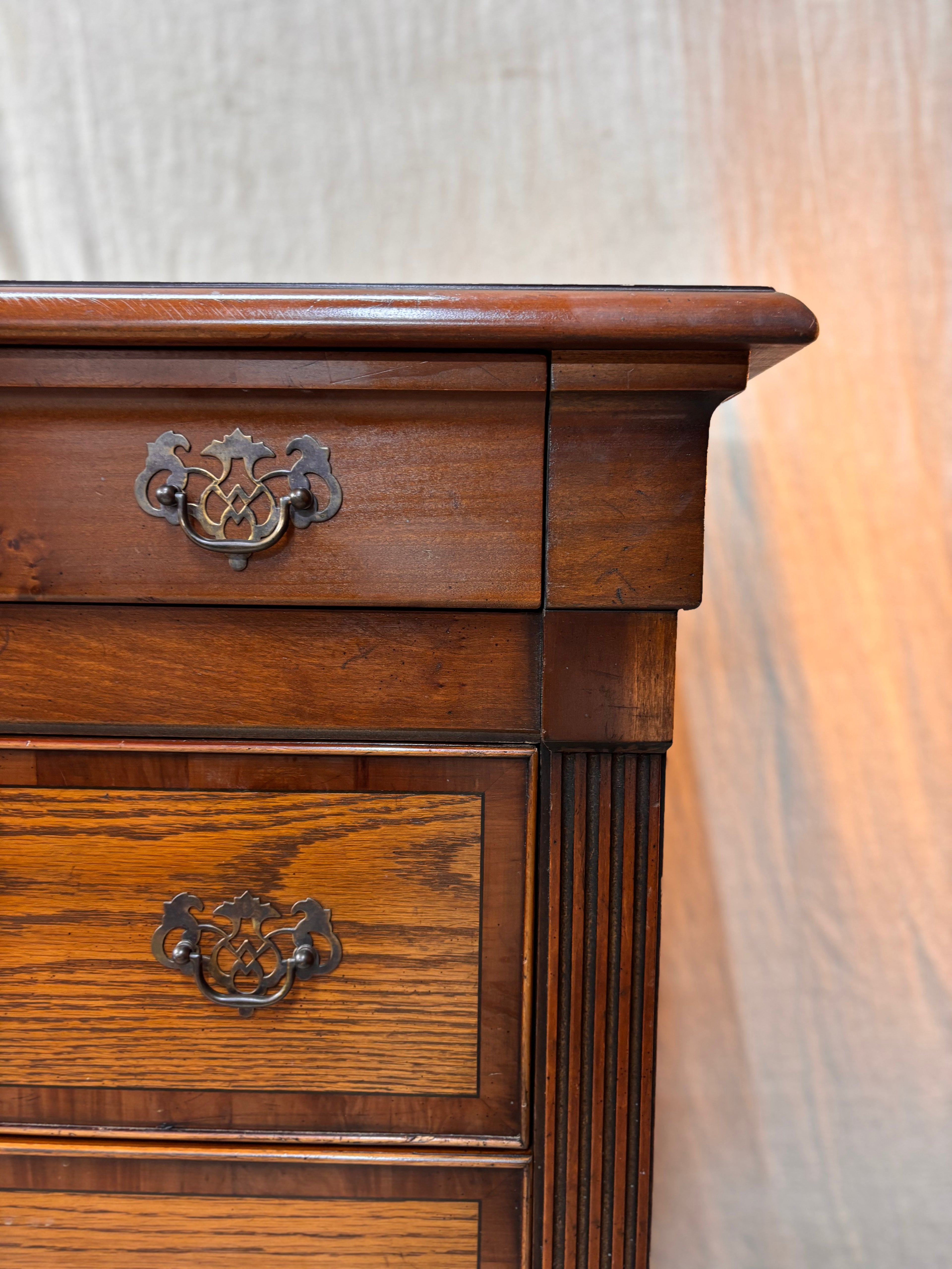Wooden dresser with two drawers and decorative handles on a white background