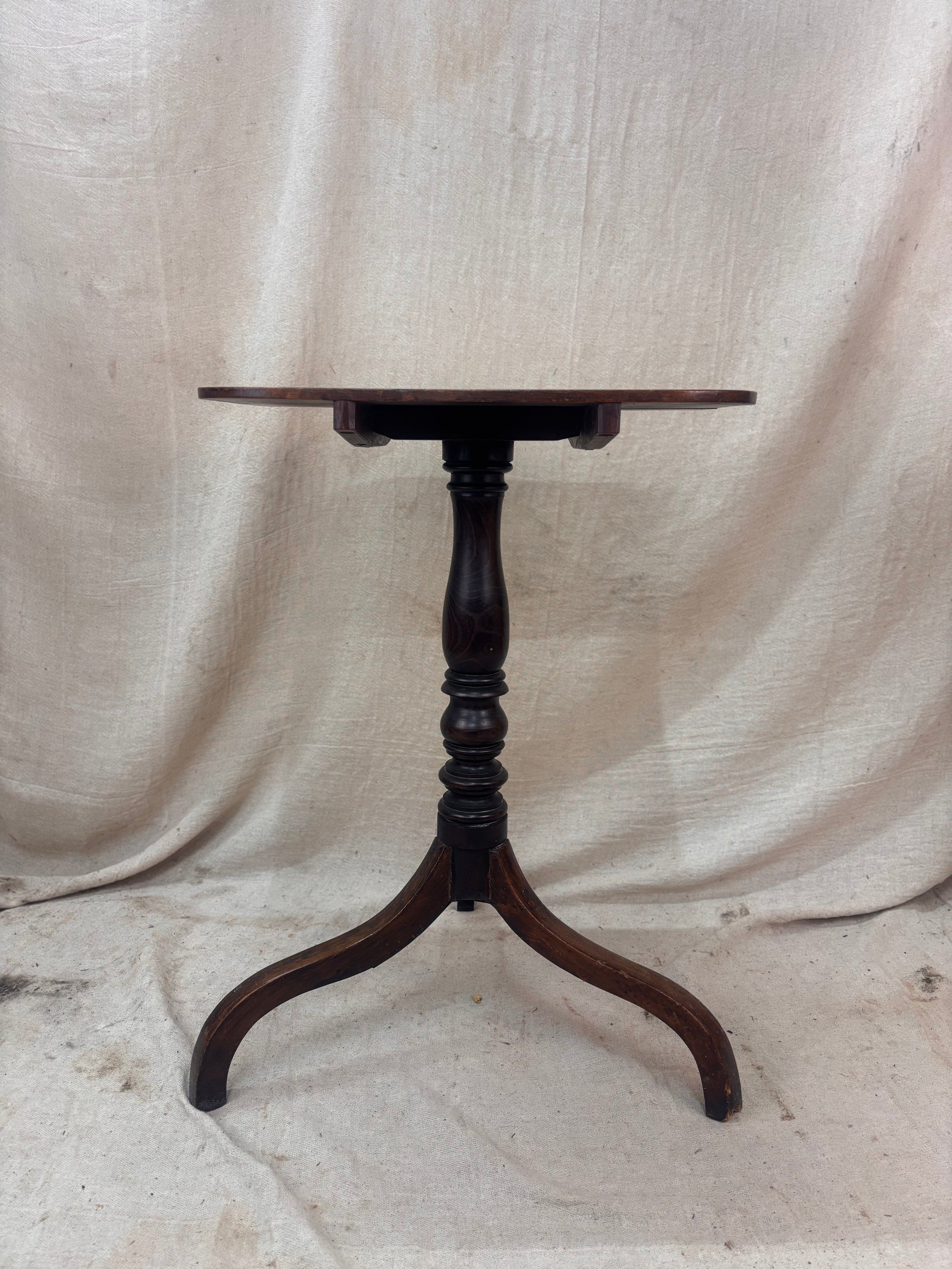 Wooden pedestal table against a beige fabric background