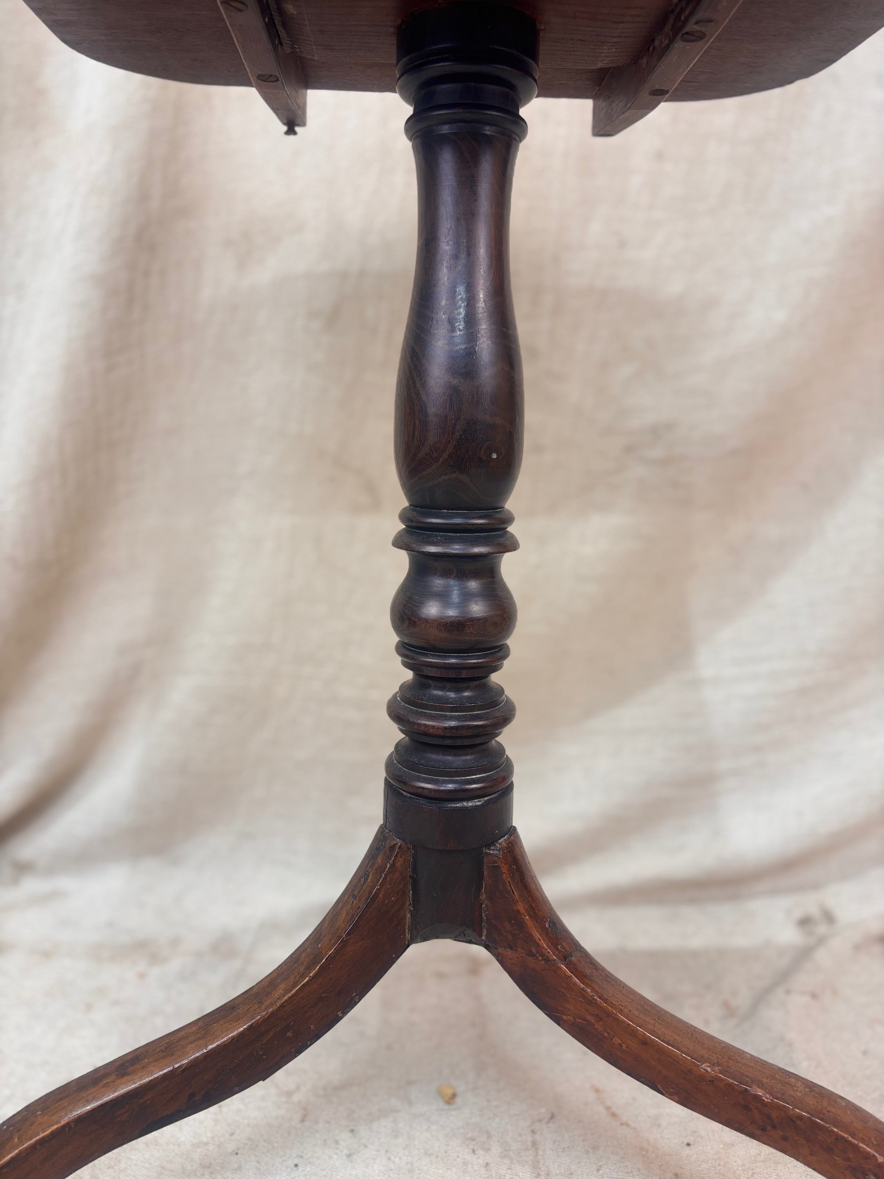 Close-up of a wooden pedestal table base on a beige fabric background