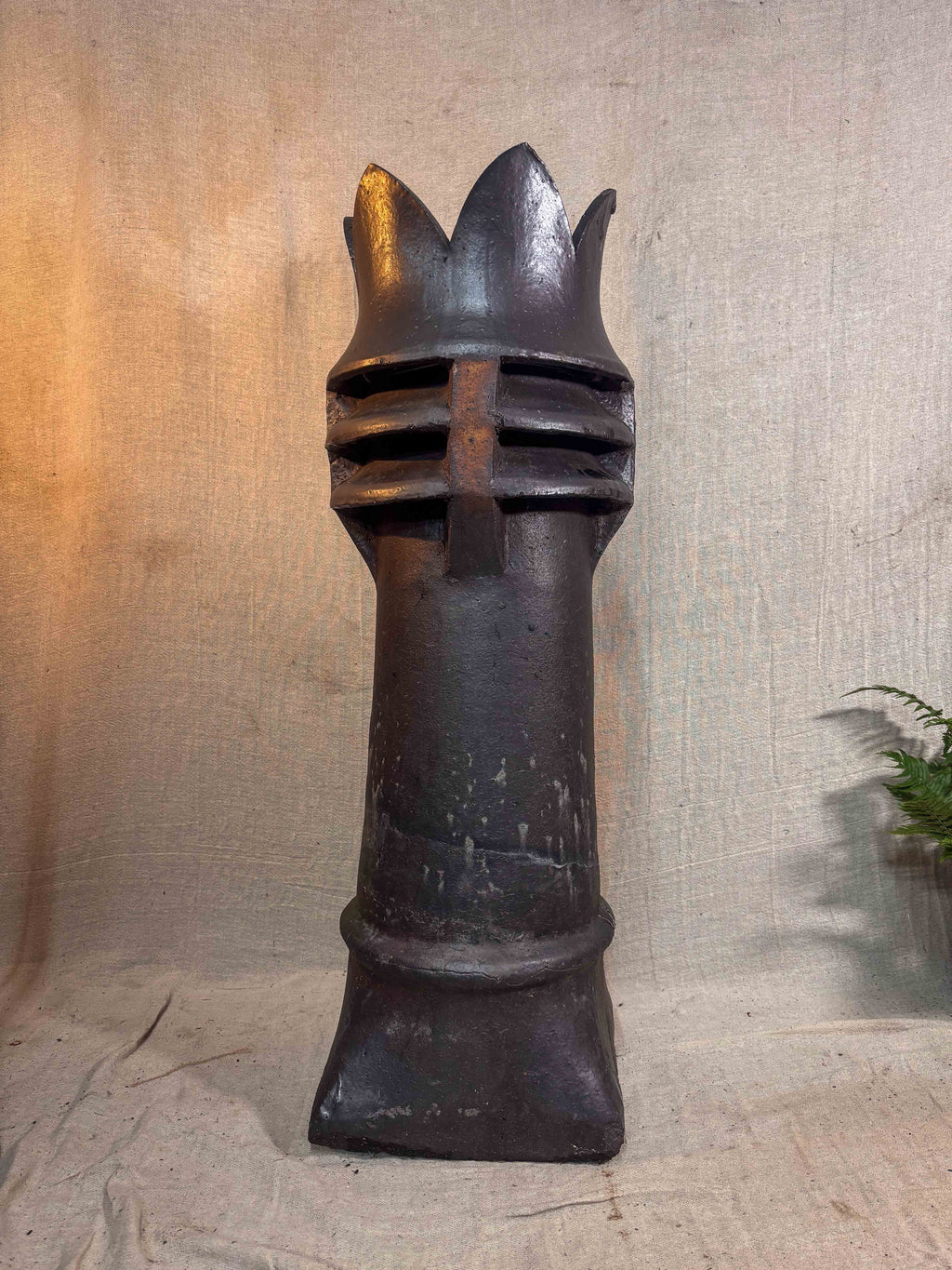 a brown glazed chimney pot on a beige cloth backdrop