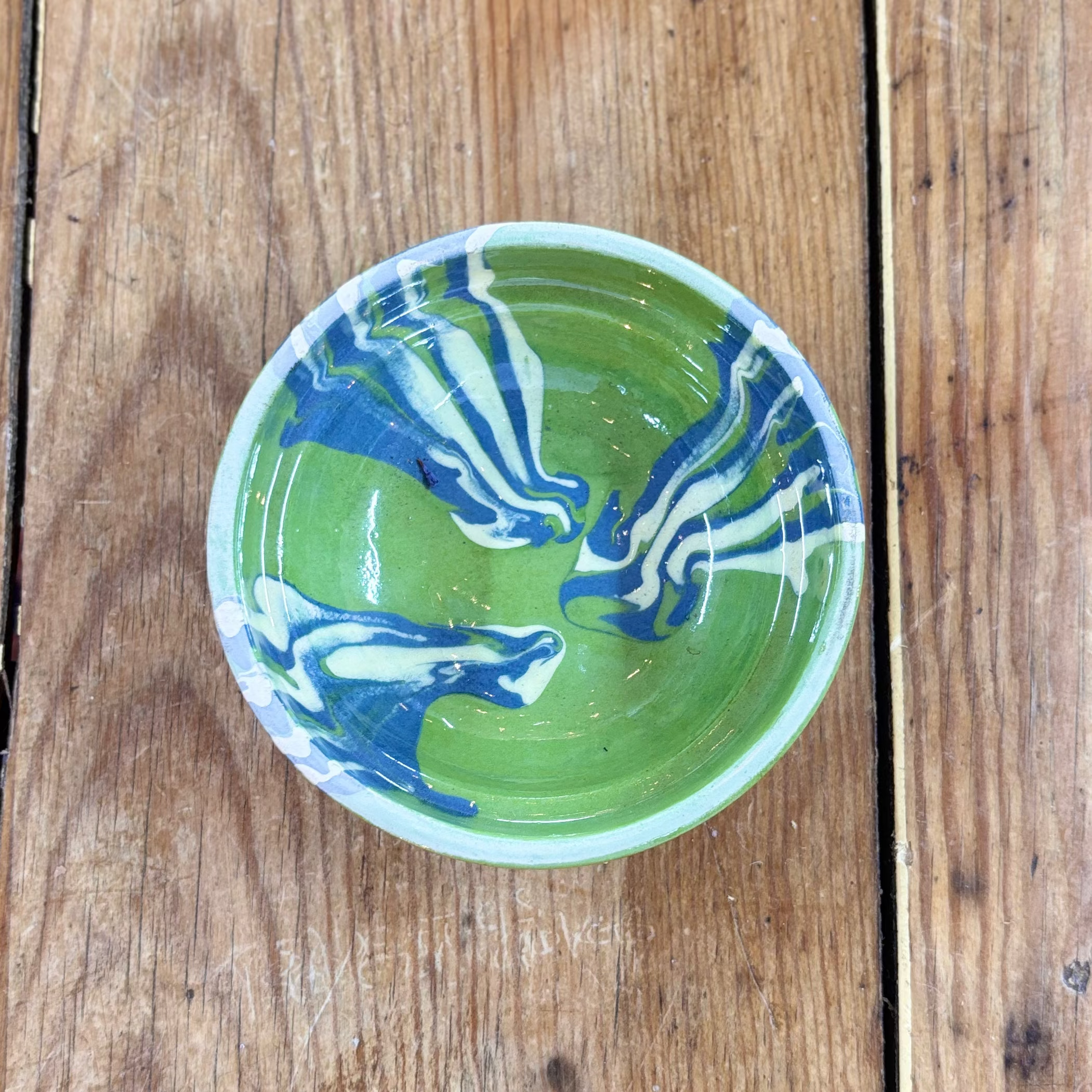 Green and blue ceramic bowl on a wooden surface